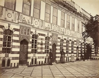 El patio de una casa judía en Stambouli, Siria, Tres domésticos se muestran cerca de las paredes del edificio