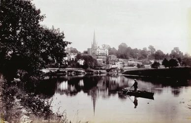 La ciudad de Ross-On-Wye, vista desde una orilla del río. En primer plano un hombre de pie en un bote de remos
