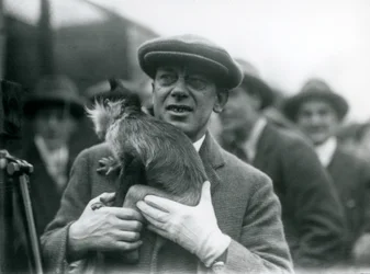 Un mangabey de cresta negra, posiblemente Freckles, con su manejador, participando en una transmisión exterior desde el Zoológico de Londres, 1925