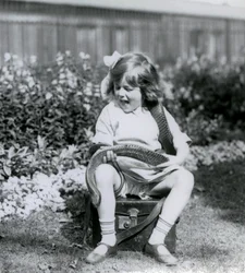 Una niña pequeña, Betty, sosteniendo una serpiente índigo oriental, mientras está sentada en un baúl de cuero, Zoológico de Londres, 1924