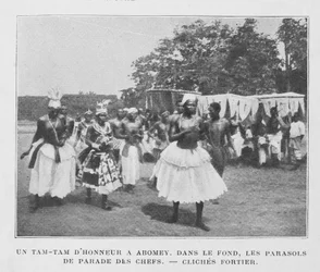Un Tam-Tam de honor en Abomey con parasoles de los jefes en el fondo