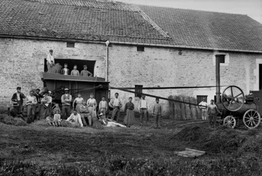 Trabajadores agrícolas y la prensa atando fardos de heno en una granja cerca de Bourmont en Haute-Marne, alrededor de 1890. Fotografía. Colección Ducos.