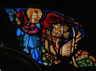 La ventana rosa oeste que representa una escena del Libro de Apocalipsis: el dragón persigue a la madre del niño varón; pero ella tiene alas con las que volar al desierto (12:13-14)