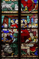 Ventana w2 que representa una escena de la Vida de la Virgen María: su nacimiento con numerosas personas, comadronas, etc.