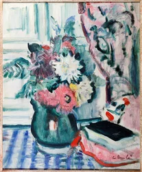 Dalias mixtas en un jarrón verde, con un libro sobre un mantel a cuadros