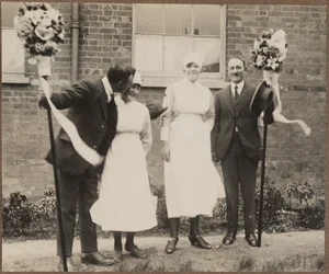Dos hombres sostienen tutti polos, de pie con dos mujeres durante el Festival Hocktide en Hungerford