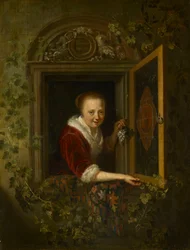 Una chica con un racimo de uvas en una ventana