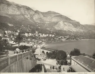 Vista panorámica de Montecarlo en Mónaco. La escena muestra varios transeúntes; a la izquierda vemos un primer plano de una balaustrada de mármol