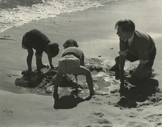 Tres niños jugando con arena en la playa.