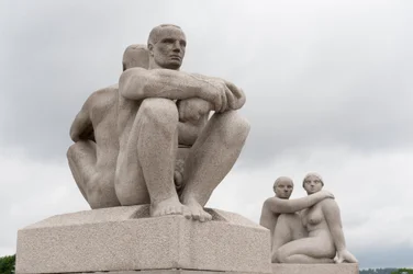 Esculturas de granito de dos hombres desnudos sentados espalda con espalda; escultura de dos mujeres en la parte trasera en el Parque Frogner, Oslo, Noruega