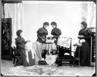 Exposición múltiple de Hannah Maynard - dos tomando el té, una sostiene una madeja de algodón, una la enrolla formando un ovillo, hacia 1895