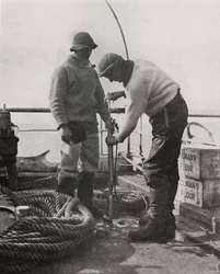 El Dr. Wilson y el Dr. Atkinson cargando el arpón