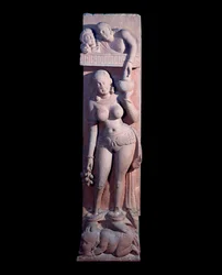Doncella montando en un enano, sosteniendo una uva y una jarra de vino (escultura de arenisca roja, Imperio Kushan)