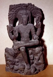 Hinduismo: representación de una de las manifestaciones de Shiva sentado en una roca, con cuatro brazos, sosteniendo un rosario, fuego, en el gesto de enseñar y en el de dar