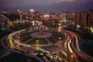 Coche, las luces de la ciudad iluminan la Plaza Baquedano. Santiago, Chile