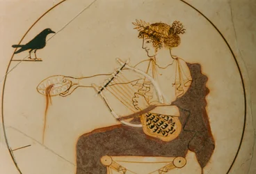 Kylix de fondo blanco decorado con una representación de Apolo. El dios está sentado sobre...