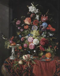 Flores en un jarrón de vidrio sobre una mesa con un tazza de plata, frutas, insectos y pájaros