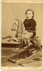 Niño con látigo en caballo de balancín