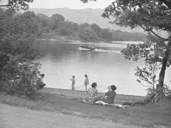 Una familia se divierte junto a un lago, barca en el lago, colinas al fondo