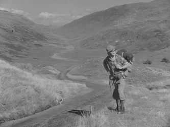 Un hombre camina con una mochila a la espalda en un paisaje de valle abierto