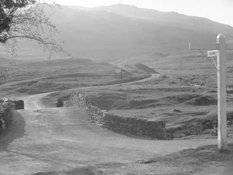 Vista de la carretera que pasa por el puerto de Hardknott con una señal que indica la dirección de Hardknott