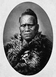 Un jefe maorí con rostro tatuado elaboradamente y capa de clima, 1902