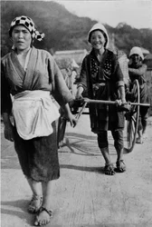 Tres generaciones de mujeres moviendo un carro con la abuela en la parte trasera, empujando, c1900, 1921