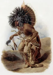 Retrato de Pehriska-Ruhpa, guerrero Minatarre en el traje de la danza del perro con un gran gorro de ropas de colores y plumas, una pipa hecha con hueso de ala de cisne, arco y flecha, grabado de René Bellet a partir de un dibujo de Karl Bodmer realizado d