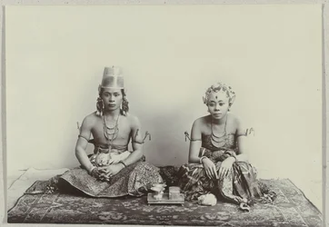 Retrato de estudio de un joven javanés sentado y una mujer vistiendo un sarong batik