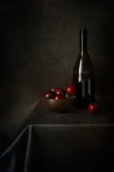 Bodegón con ciruelas y una botella