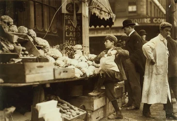 Un niño trabajando en un puesto de frutas y verduras en Boston, Massachusetts.