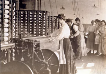 Jóvenes trabajando en una máquina de hilar en una fábrica de algodón, Carolina del Sur, 1908