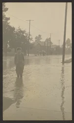 [Niño de pie en una calle inundada]
