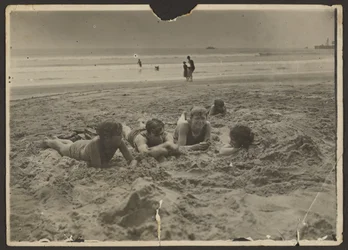[Niños tumbados en la arena de la playa]