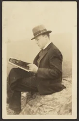 Hombre leyendo una revista sobre una roca