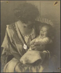 [Madre con bata bordada y un bebé]