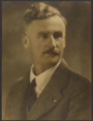 [Retrato de un hombre con alfiler de solapa blanco]