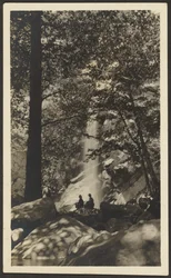 [Dos figuras junto a una cascada en el bosque]