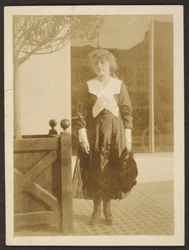 [Mujer de pie en la acera]