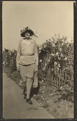 [Mujer caminando por la valla con flores]