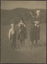 [Mujer y tres niños en el campo]