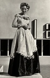 Modelo en vestido de gala creado por la casa de alta costura "Graldi". El artículo se caracteriza por un escote bajo y una falda completa decorada con apliques florales.