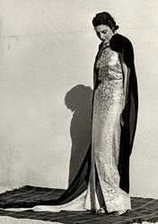 Modelo en vestido de noche creado por la casa de alta costura italiana "Dragoni". El artículo se complementa con un largo manto de terciopelo.