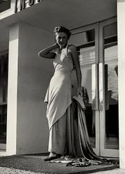 Modelo en vestido de noche creado por la casa de alta costura "Graldi". El artículo se caracteriza por un escote pronunciado adornado con tirantes de pedrería y una larga cola.