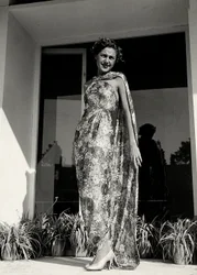 Modelo con un vestido largo con patrón floral creado por la casa de alta costura "Graldi". El artículo se complementa con un manto del mismo tejido.