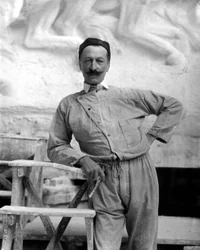 Retrato del famoso escultor Pietro Canonica con ropa de trabajo. El artista posa en su estudio sosteniendo una herramienta de su oficio en su mano derecha