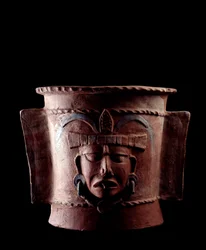 Arte precolombino, civilización maya, periodo clásico tardío: urna funeraria cilíndrica de arcilla decorada con un rostro humano. Procedente de Quiché, Guatemala. Dimensiones: altura 38.5 x diámetro 39,5 cm. Guatemala, Museo Nacional de Arqueología y