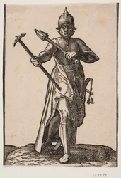 Soldado con casco de pie, visto de frente; en la mano derecha un martillo de guerra, en la mano izquierda una maza, la pierna y el pie traseros torcidos en relación con los delanteros; al lado izquierdo una espada