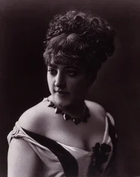 Retrato de mujer. Rostro de una mujer que lleva un escote y un collar con colgantes en forma de corazón.