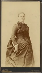 [Mujer no identificada de pie con vestido largo]
